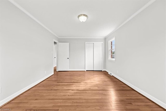 unfurnished bedroom with crown molding, light hardwood / wood-style floors, and a closet