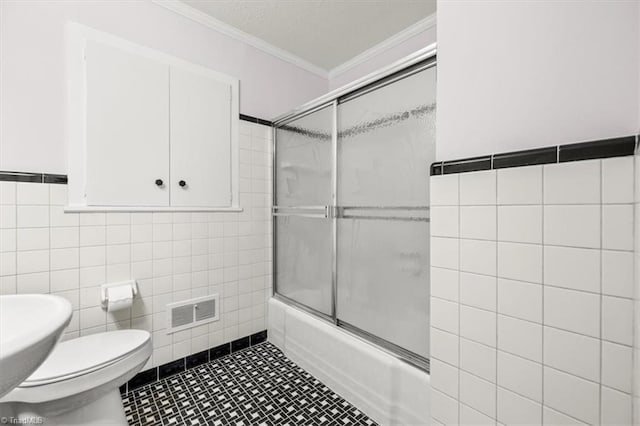 full bathroom featuring toilet, sink, crown molding, bath / shower combo with glass door, and tile walls