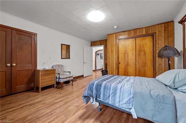 bedroom with wood walls and light wood-type flooring