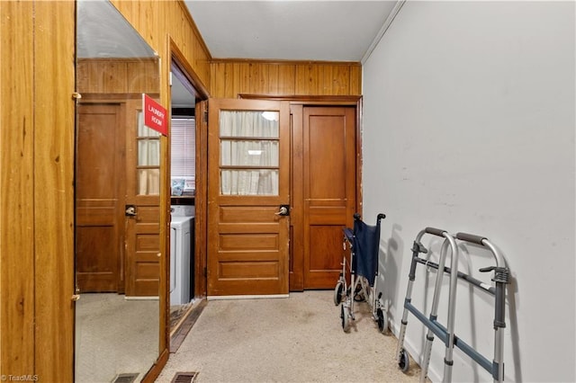 entryway with light colored carpet, crown molding, washer / clothes dryer, and wooden walls