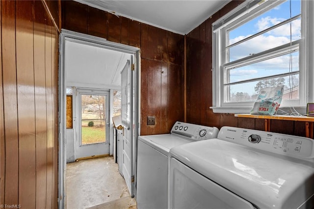 clothes washing area featuring washer and clothes dryer and wood walls