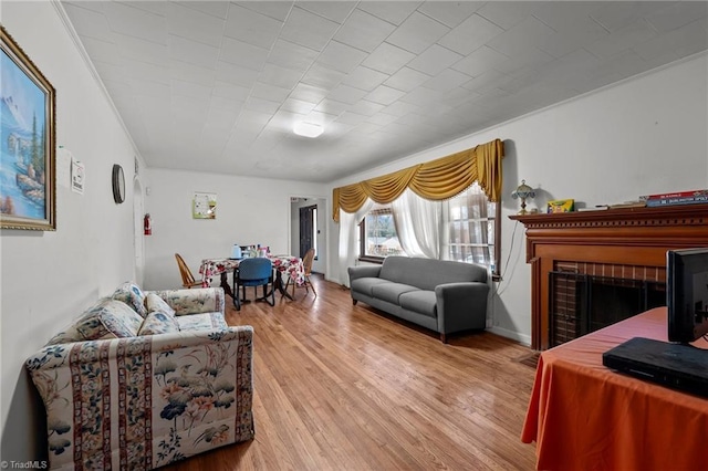 living room featuring hardwood / wood-style flooring, a fireplace, and crown molding