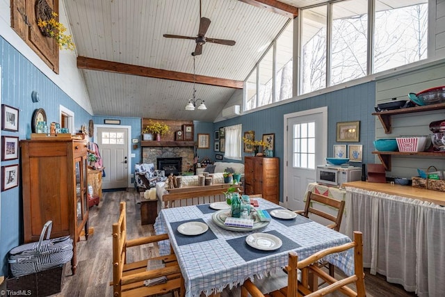 dining area featuring a fireplace, beam ceiling, wood finished floors, and high vaulted ceiling