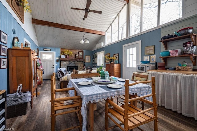 dining room with a ceiling fan, wood finished floors, high vaulted ceiling, a stone fireplace, and beamed ceiling