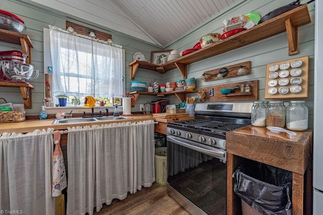 kitchen with lofted ceiling, open shelves, stainless steel range with gas cooktop, and a sink