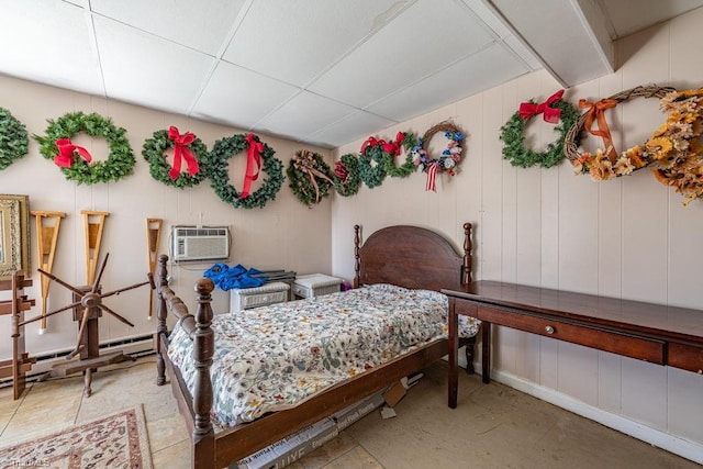 bedroom with a drop ceiling, a wall mounted air conditioner, and a baseboard heating unit