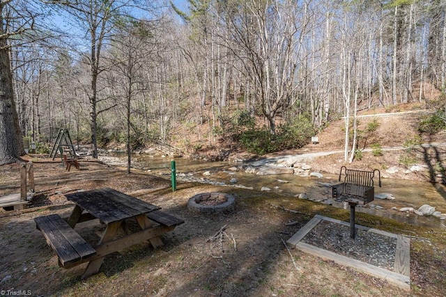 view of yard with a wooded view and an outdoor fire pit