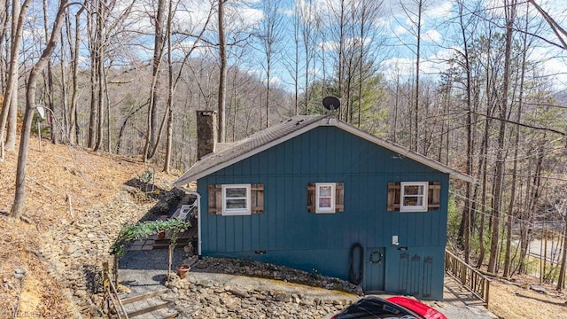 view of home's exterior with a wooded view and a chimney