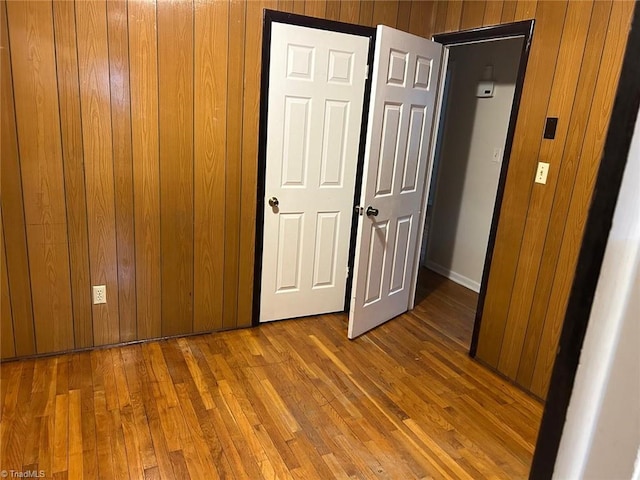 unfurnished bedroom with hardwood / wood-style flooring and wooden walls