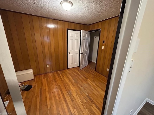 unfurnished bedroom featuring hardwood / wood-style floors, wooden walls, and a textured ceiling