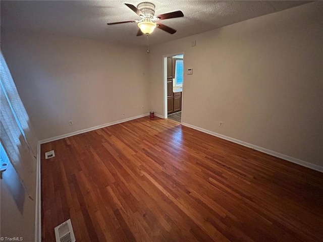 unfurnished room featuring a textured ceiling, dark hardwood / wood-style floors, and ceiling fan