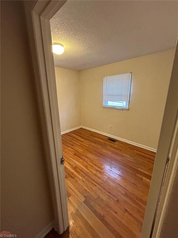 empty room with hardwood / wood-style flooring and a textured ceiling