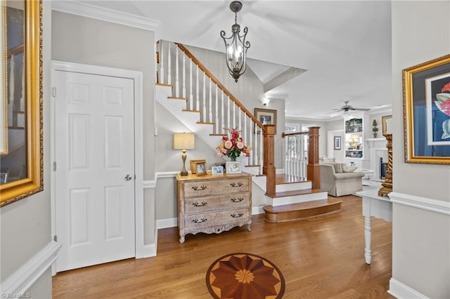 entrance foyer with wood finished floors, a ceiling fan, a fireplace, stairway, and baseboards