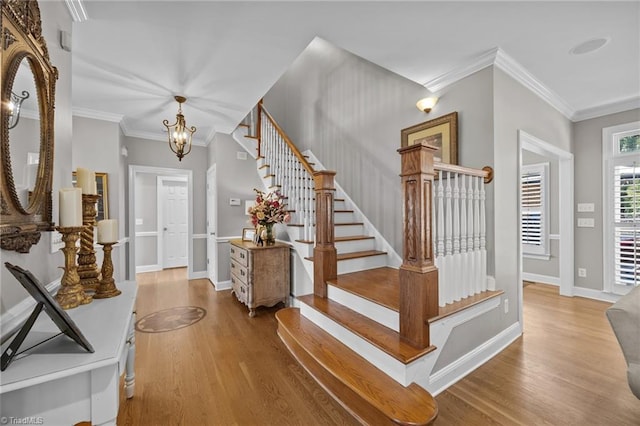 foyer entrance with a chandelier, stairway, wood finished floors, and ornamental molding