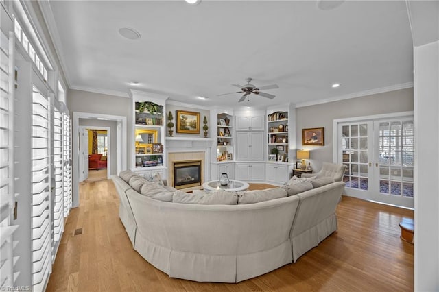 living room featuring recessed lighting, a wealth of natural light, light wood finished floors, and a glass covered fireplace