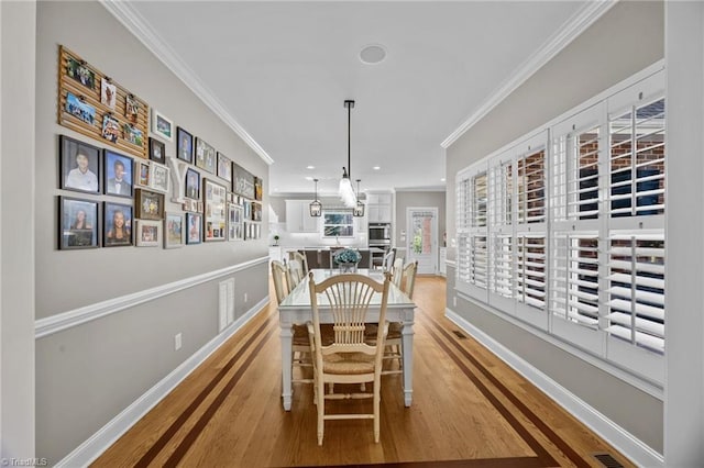 dining space with crown molding, light wood-style floors, baseboards, and recessed lighting