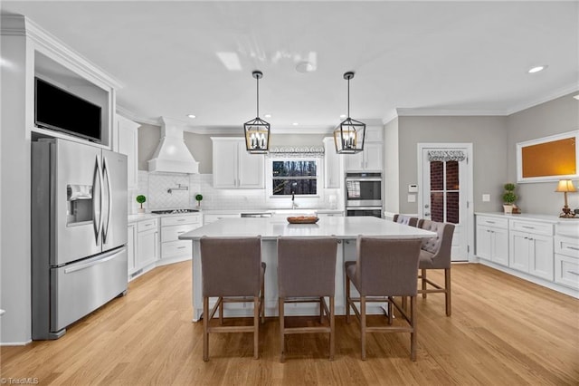 kitchen with premium range hood, stainless steel appliances, light wood-type flooring, light countertops, and white cabinets