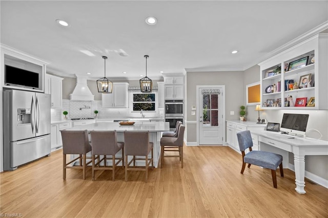kitchen featuring premium range hood, light countertops, white cabinets, and appliances with stainless steel finishes