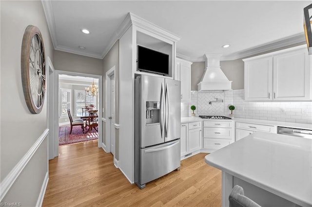 kitchen with custom exhaust hood, white cabinetry, gas cooktop, stainless steel fridge with ice dispenser, and crown molding
