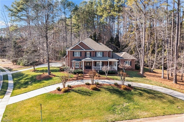traditional home featuring covered porch, curved driveway, and a front lawn