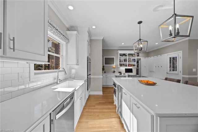 kitchen with a sink, stainless steel appliances, an inviting chandelier, open floor plan, and white cabinets