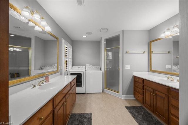 full bathroom featuring a sink, two vanities, a stall shower, and independent washer and dryer