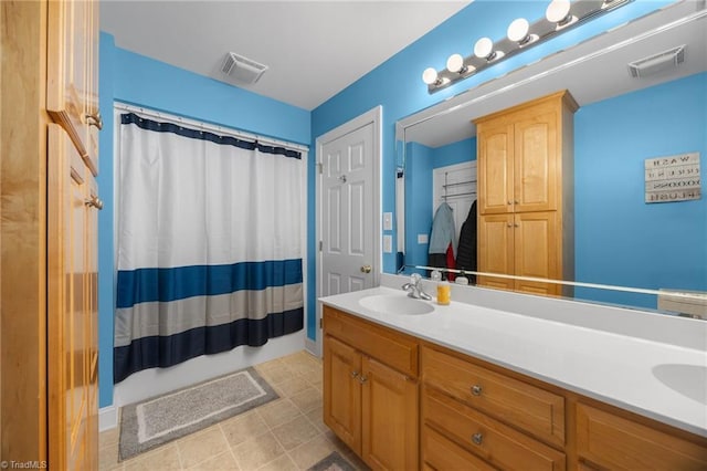 full bath with double vanity, curtained shower, visible vents, and a sink