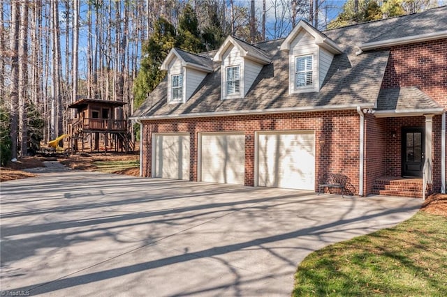 exterior space with a playground, brick siding, driveway, and a garage
