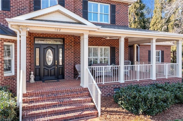 view of exterior entry featuring covered porch and brick siding