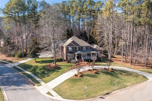 view of front of property featuring covered porch, a front yard, and curved driveway
