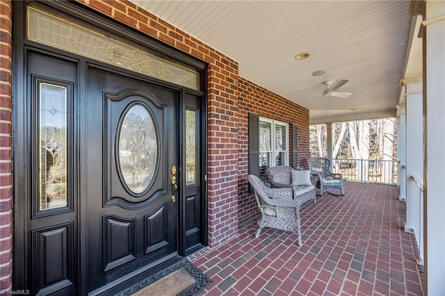 property entrance featuring a porch, brick siding, and ceiling fan