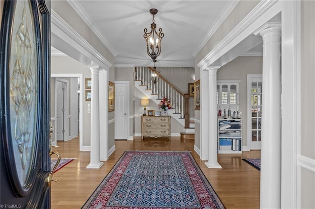 entrance foyer with a notable chandelier, wood finished floors, decorative columns, and stairs