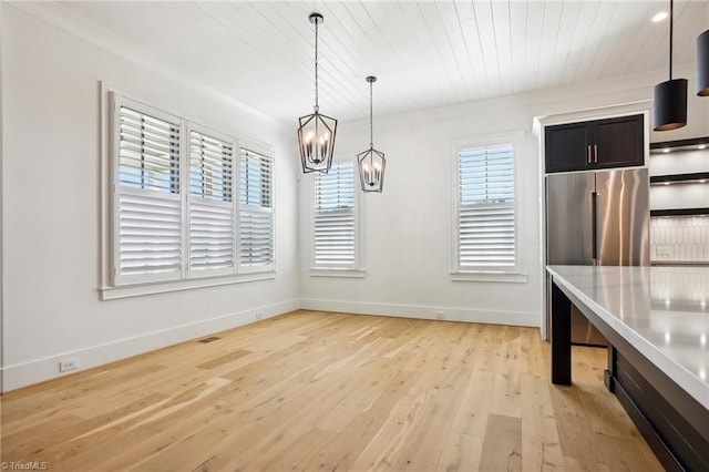 unfurnished dining area with baseboards, a chandelier, wood ceiling, and light wood-style floors