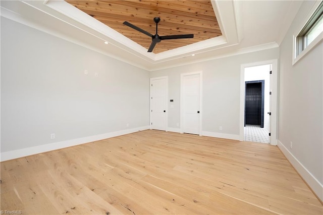 spare room with a tray ceiling, light wood-style floors, wood ceiling, and baseboards