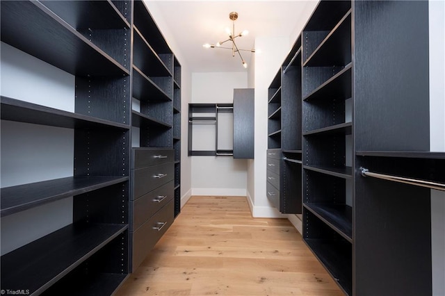 walk in closet featuring light wood-type flooring and a chandelier