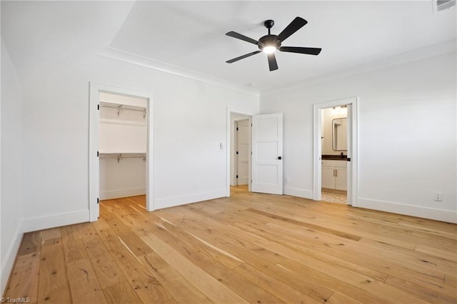 unfurnished bedroom featuring light wood-style flooring, visible vents, baseboards, a spacious closet, and crown molding