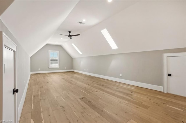 additional living space with baseboards, visible vents, a ceiling fan, lofted ceiling with skylight, and light wood-type flooring