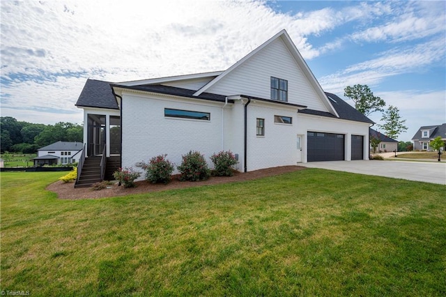 view of home's exterior featuring a sunroom, a lawn, and concrete driveway