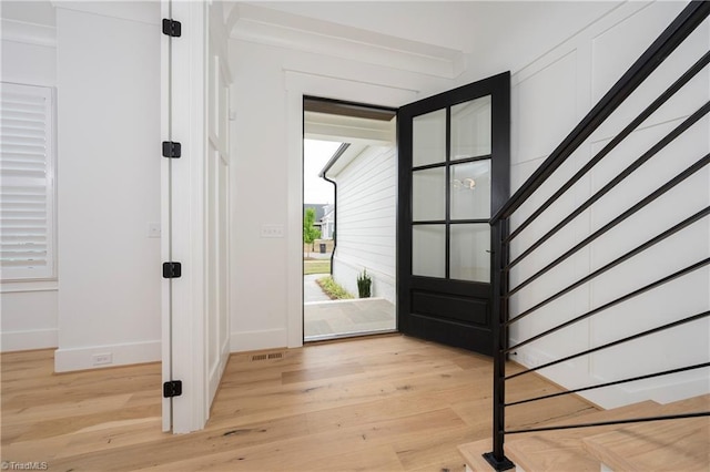 foyer entrance with baseboards, visible vents, and light wood-style floors