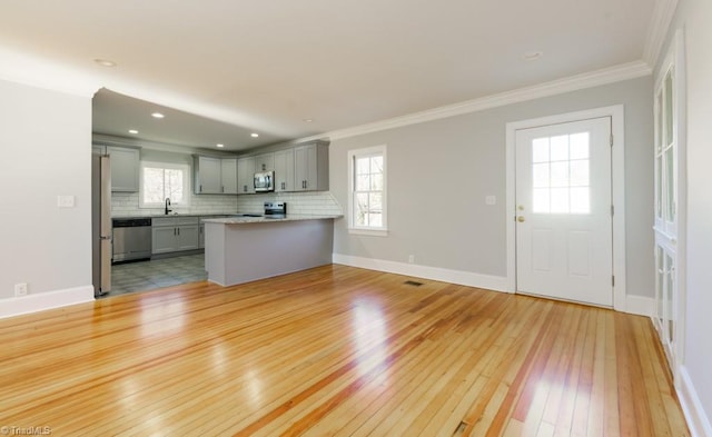 unfurnished living room featuring crown molding, a wealth of natural light, and light hardwood / wood-style flooring