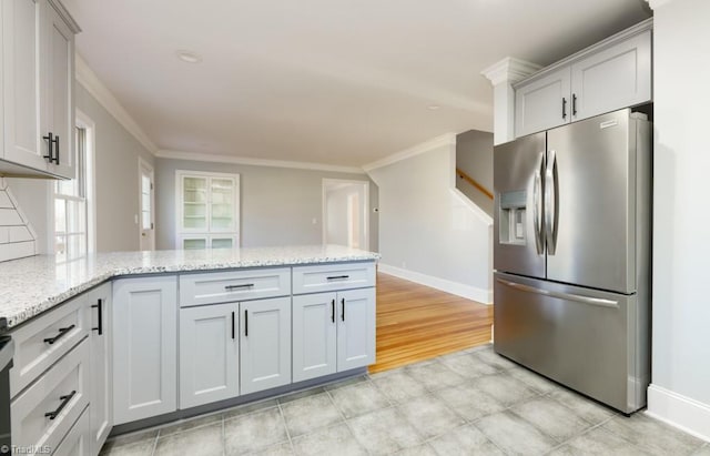 kitchen with crown molding, light stone counters, kitchen peninsula, and stainless steel refrigerator with ice dispenser