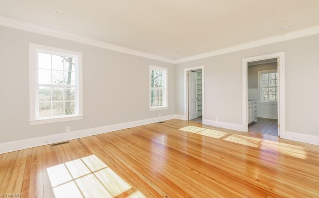 empty room featuring hardwood / wood-style floors, plenty of natural light, and ornamental molding