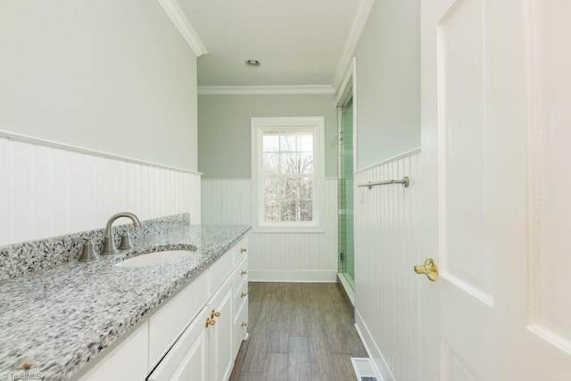 bathroom with vanity, hardwood / wood-style flooring, a shower with door, and ornamental molding