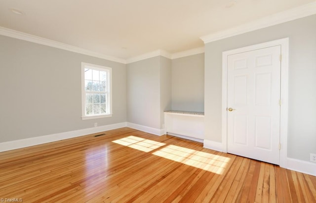 spare room featuring light wood-type flooring and crown molding