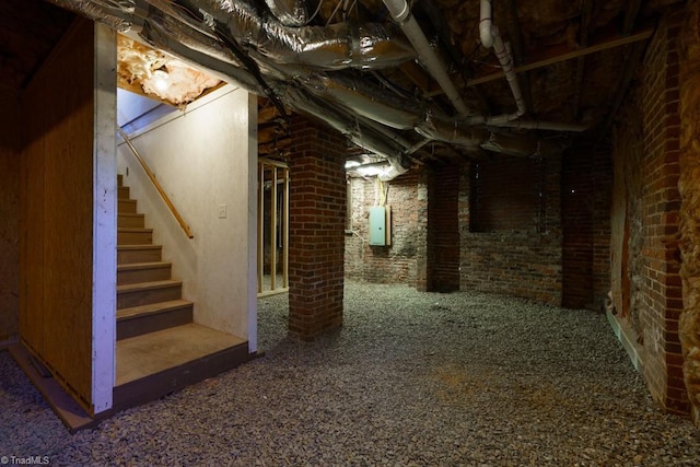 basement featuring electric panel and brick wall