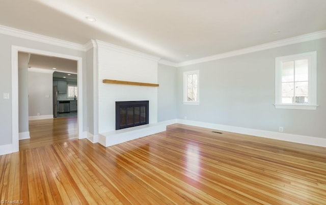 unfurnished living room featuring crown molding, a large fireplace, and light wood-type flooring