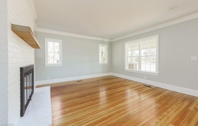 unfurnished living room with a wealth of natural light, crown molding, a fireplace, and light hardwood / wood-style flooring