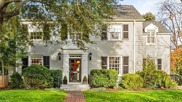 colonial-style house featuring a front lawn