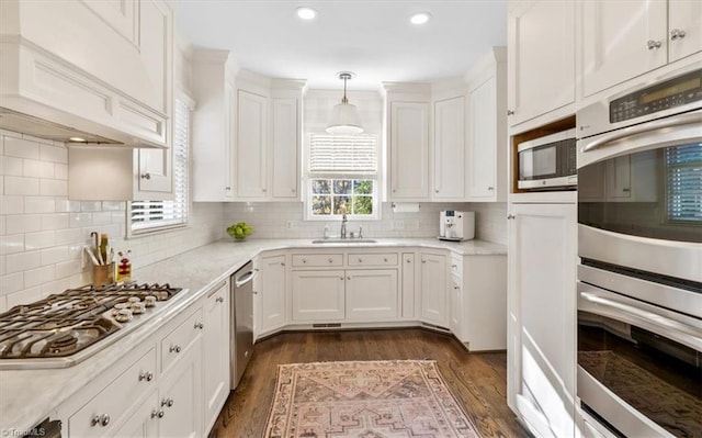 kitchen featuring white cabinetry, sink, backsplash, decorative light fixtures, and appliances with stainless steel finishes