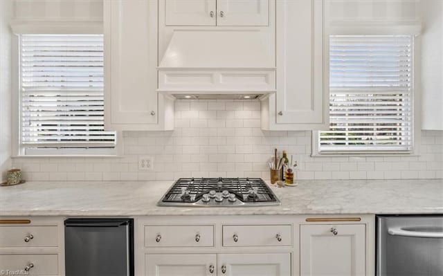 kitchen featuring light stone countertops, premium range hood, white cabinets, and stainless steel gas cooktop